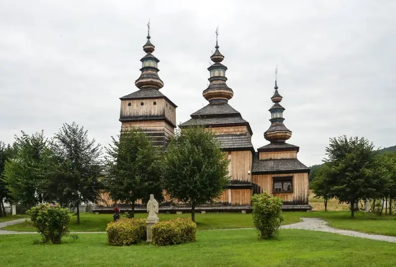 Drewniana cerkiew z trzema kopułami, otoczona zielenią. Wspaniałe krempna atrakcje dla miłośników historii i architektury.