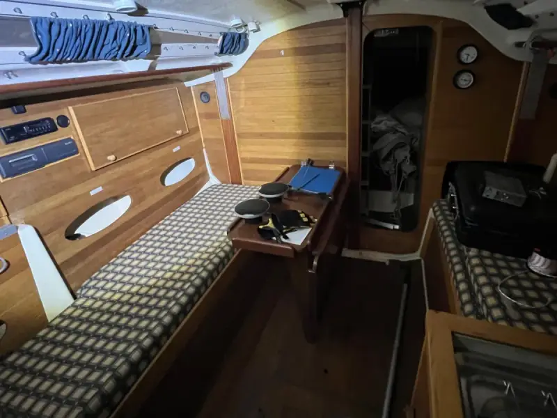 Intérieur d'un voilier Trident 80. Banquette, table pliante, rangement et couchette.
