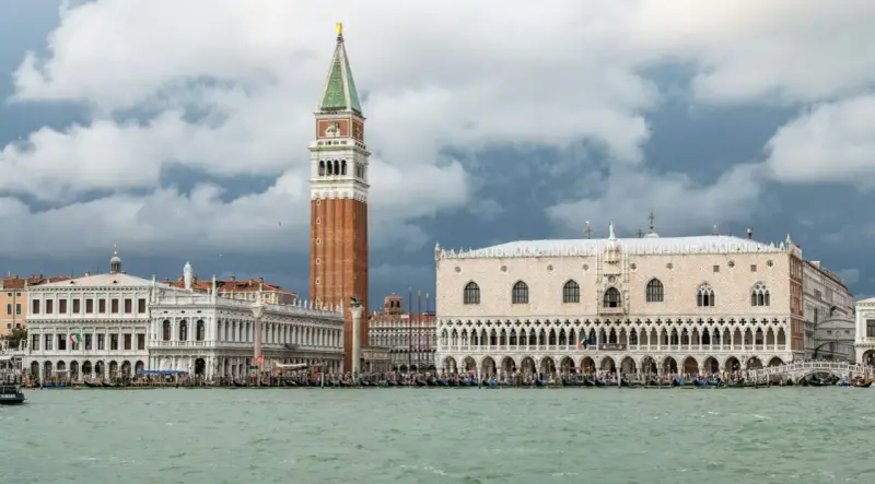 Weneckie budowle, w tym Pałac Dożów i Kampanila, na tle burzowych chmur. Venezia to miasto, które zachwyca.
