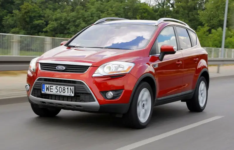 Czerwony Ford Kuga, idealny SUV do 40 tys. zł, jedzie po drodze.