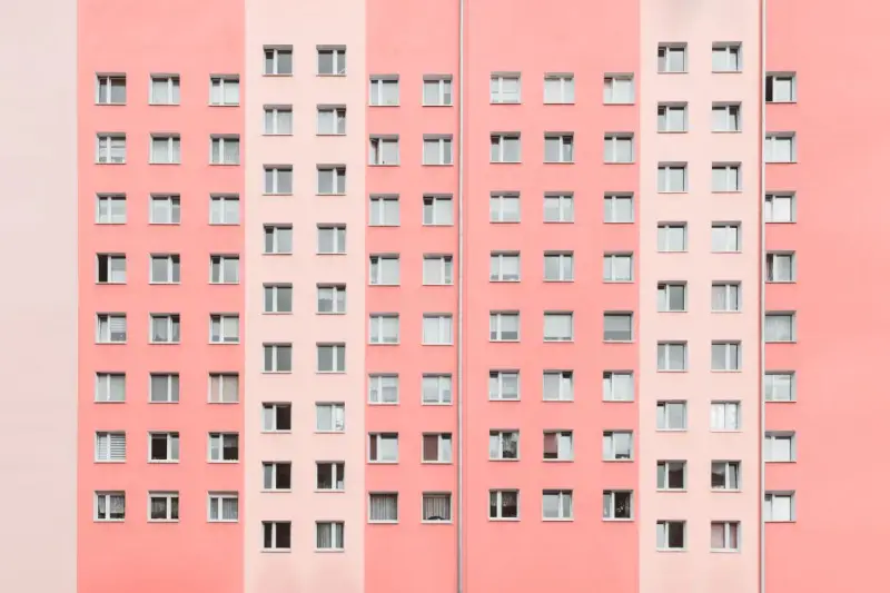 Pasteloza w architekturze: fasada bloku mieszkalnego w odcieniach różu i brzoskwini, z rzędami okien.