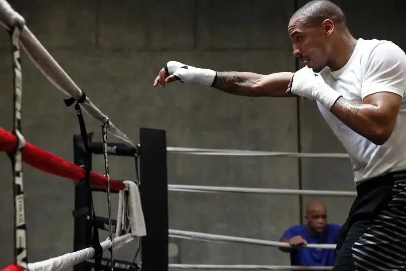 Un boxeur s'entraîne en shadow boxing dans un ring, concentré sur ses mouvements.