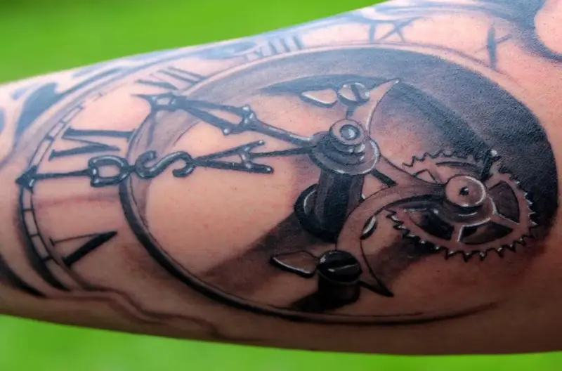 Un tatouage réaliste d'une montre à gousset avec des engrenages complexes. Une œuvre d'art qui témoigne d'une formation dessin tatouage.