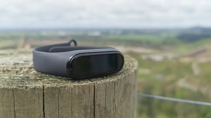 Czarny Mi Band 4 na drewnianym słupku, idealny do śledzenia aktywności. To najlepsza aplikacja do Mi Band 4 dla aktywnych osób.
