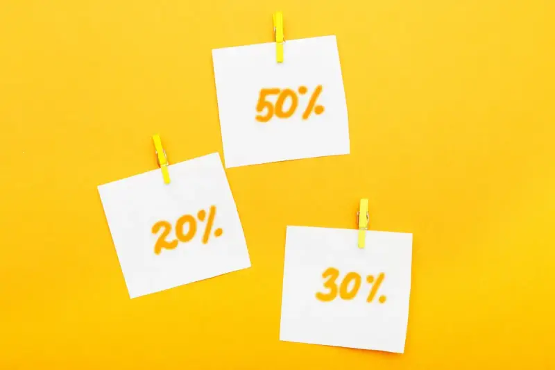Trzy karteczki z napisami 20%, 30% i 50% przyczepione żółtymi spinaczami. Idealne zniżki dla emerytów!