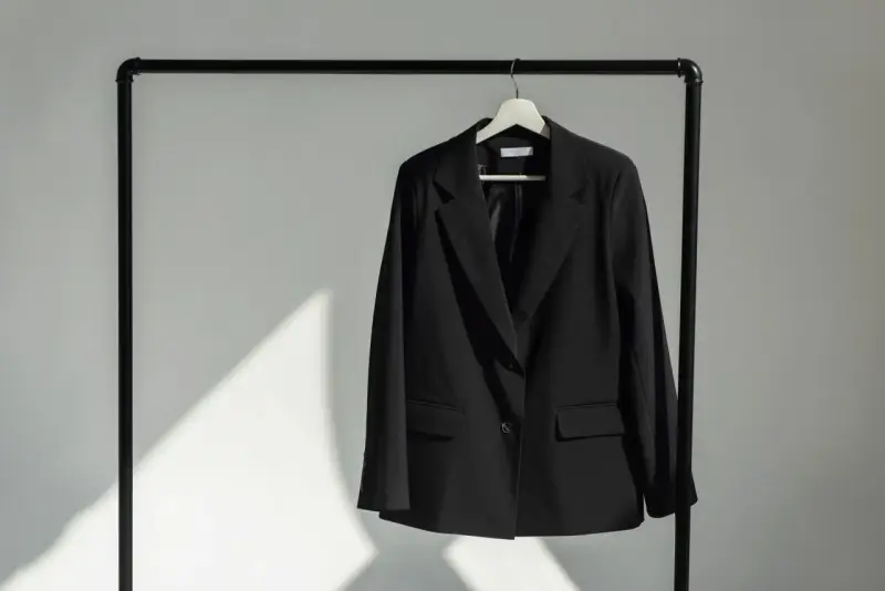 Schwarzer Blazer hängt auf einem Kleiderbügel. Zeit, den Blazer zu waschen und frisch zu machen.