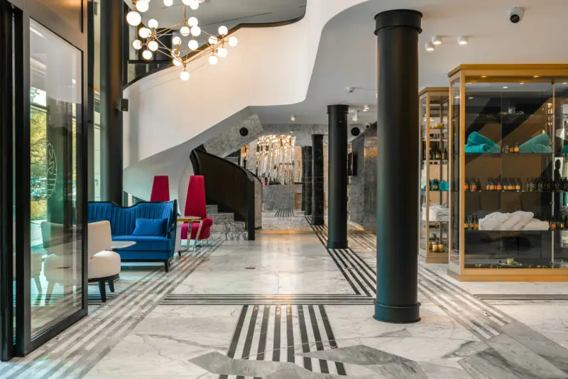 Eleganckie wnętrze bankietowe z niebieską kanapą i czerwonymi fotelami. Przyczyny powrotu do stylistyki art deco w nowoczesnych wnętrzach bankietowych widać w geometrycznych wzorach i luksusowych materiałach.