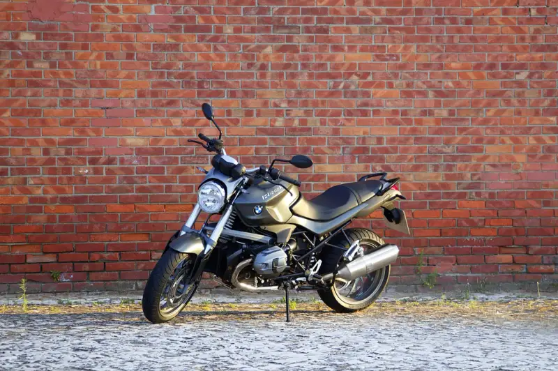 Szary motocykl BMW R1200R na tle ceglanej ściany. Poznaj jego dane techniczne i możliwości.