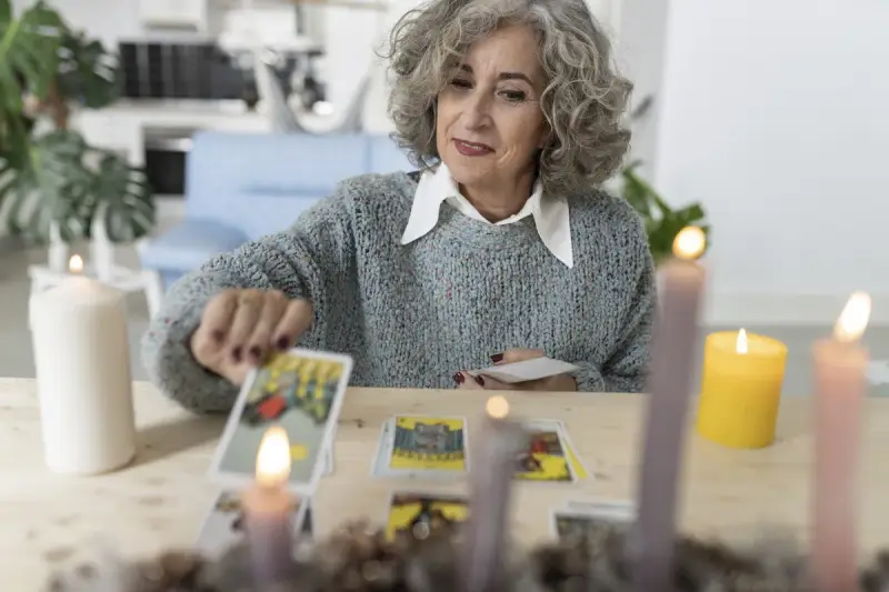 Kobieta z siwymi włosami układa karty tarot, szukając wskazówek dotyczących umiarkowanie uczuć.