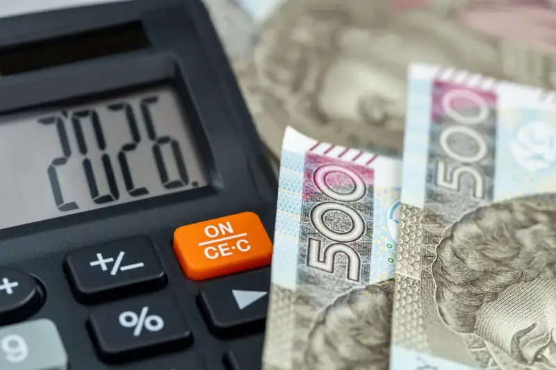 Kalkulator pokazuje 20,26, a obok leżą banknoty 500 zł. To może być odpowiedź na pytanie, ile zarabia pomocnik dekarza na godzinę.