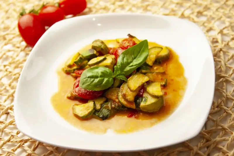 Zucchine in umido con pomodorini e basilico fresco, un piatto estivo profumato e saporito.