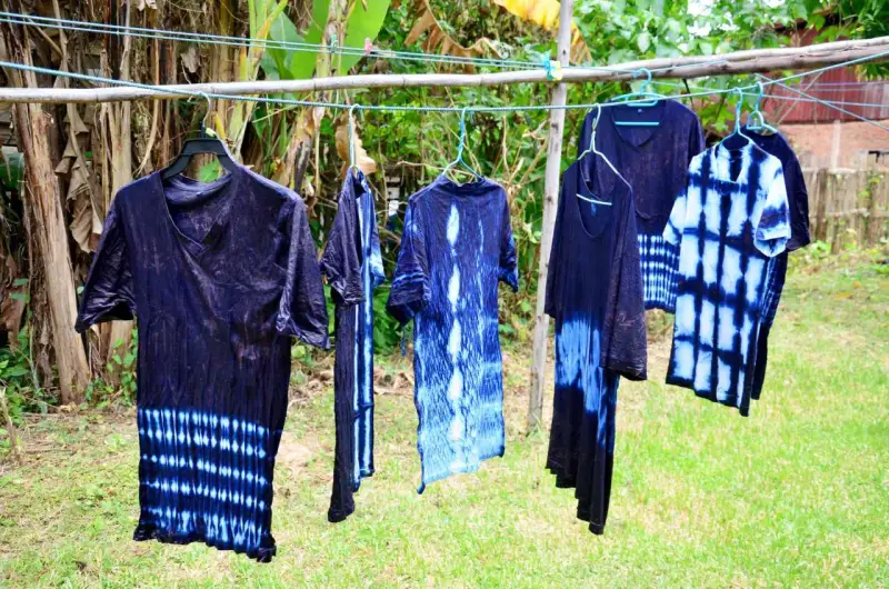 Abiti con motivi tie-dye blu e bianchi, pronti per asciugare dopo aver provato a tingere tessuti sintetici.
