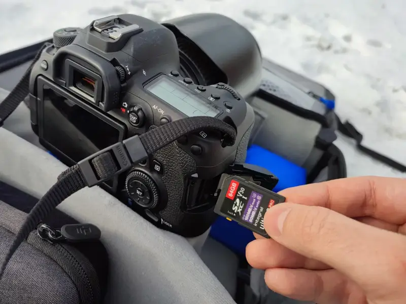 Dłoń wkłada kartę pamięci 64GB do aparatu. Ile to zdjęć? Z pewnością mnóstwo!