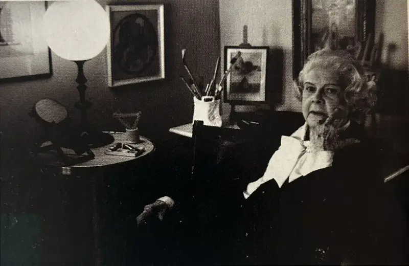 Colette Gueden, artiste peintre, dans son atelier, entourée de ses œuvres et de son matériel.