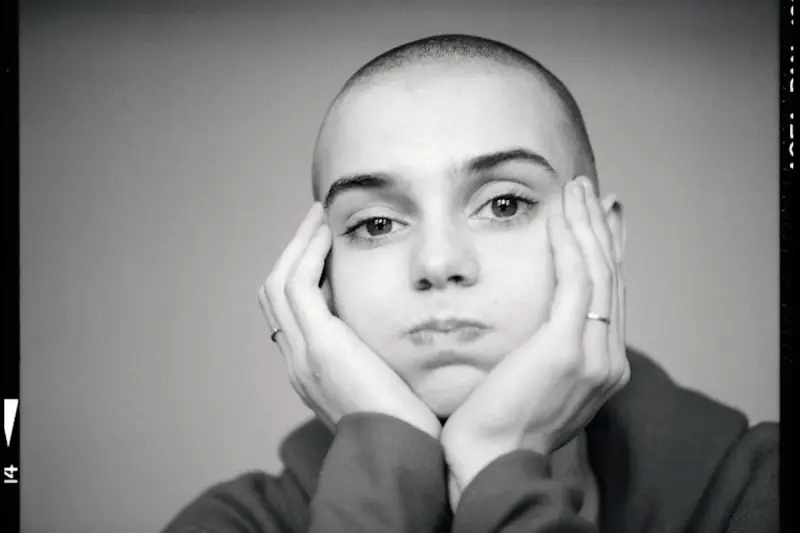 Sinead O'Connor z dłońmi opartymi o policzki, zamyślona.