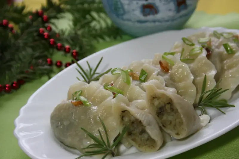 Pyszne pierogi ukraińskie, udekorowane szczypiorkiem i rozmarynem, na świątecznym stole.