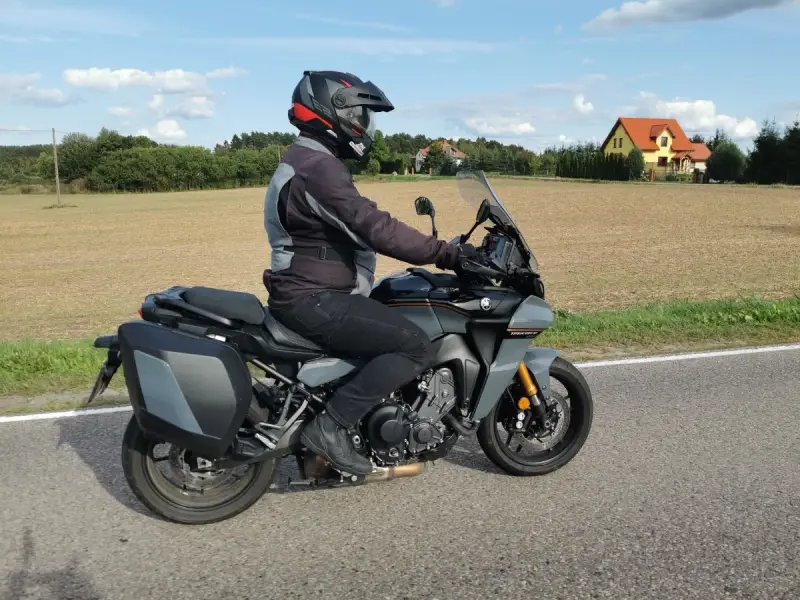 Motocyklista na Yamaha Tracer 900, z sakwami, w kasku, jedzie po drodze. Dane techniczne tego modelu są imponujące.
