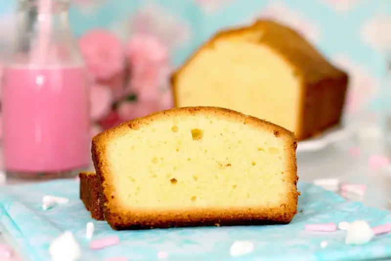 Rebanadas de bizcocho esponjoso, perfecto para tu próxima receta. Acompañado de un batido rosa y flores.