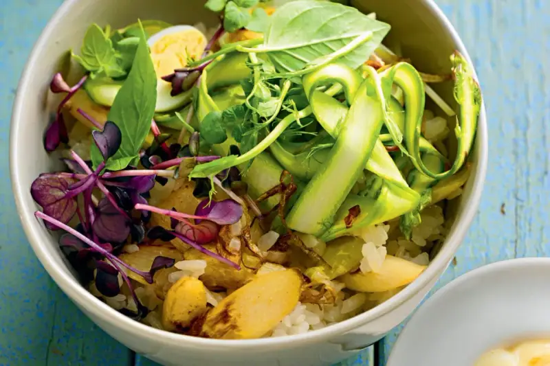 Eine bunte Spargel Bowl mit Reis, Ei, Sprossen und frischen Kräutern, appetitlich angerichtet.