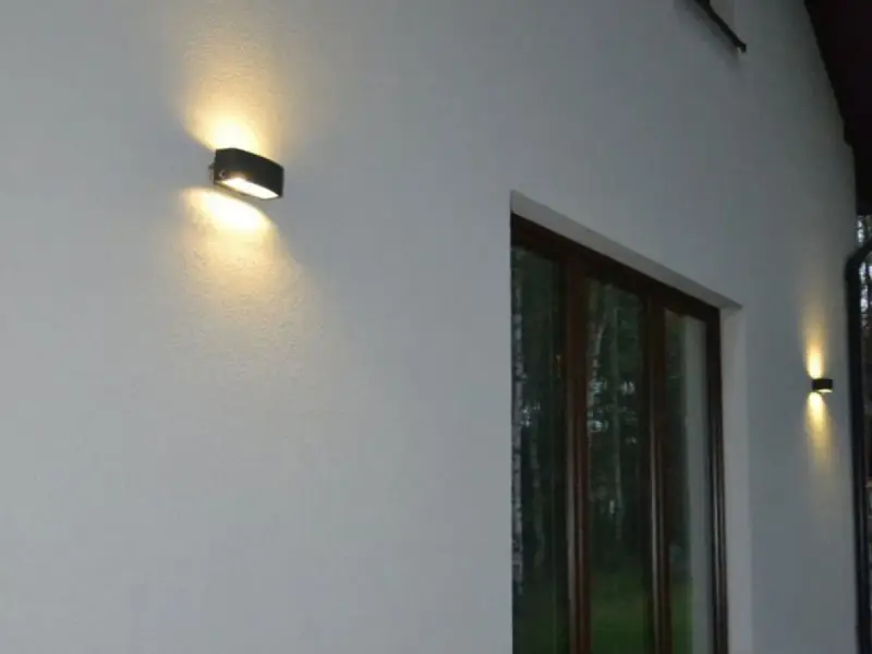 Nierówności na elewacji pod światło, podkreślone przez dwa kinkietowe punkty świetlne.