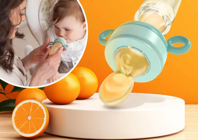 Mama karmi dziecko smoczkiem do owoców, który wygląda jak mały dzbanuszek z pomarańczowym płynem. Obok pomarańcze.