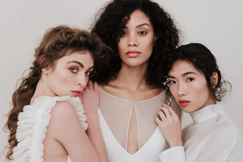 Trois femmes aux visages lumineux, prêtes pour un soin visage avant mariage. Leur peau est radieuse, leurs regards doux.