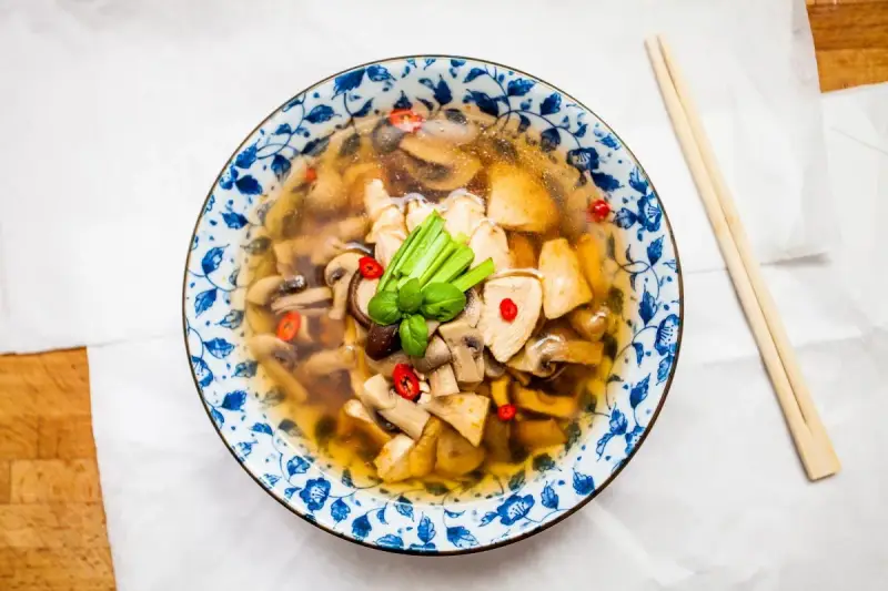 Aromatyczna zupa tom yum z kurczakiem i grzybami, ozdobiona chili i zieloną cebulką. Idealna na chłodne dni.