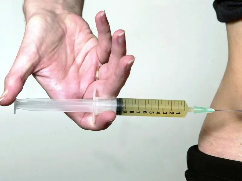 Spritze statt thrombose tabletten: Eine Spritze wird in den Bauch eingeführt, um eine Thrombose zu behandeln, besonders wichtig auf einem langen Flug.