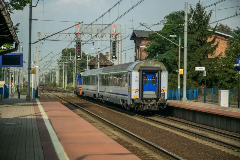Pociąg Polregio z wygodnymi miejscami siedzącymi stoi na peronie.