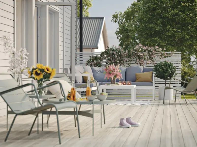 En härlig altan runt huset med bekväma möbler, solrosor och en inbjudande atmosfär för avkoppling.
