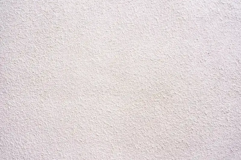 Texture d'un corps d'enduit chaux blanc, légèrement granuleux, évoquant la fraîcheur et la pureté d'une façade traditionnelle.