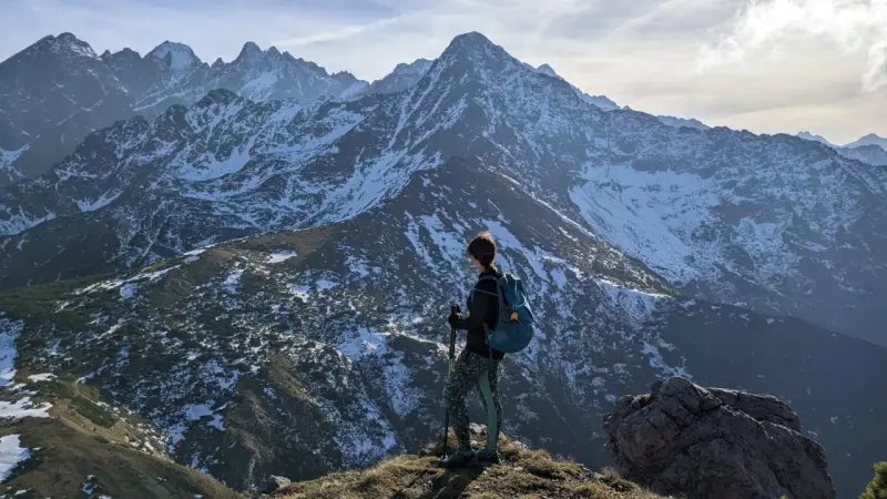 Osoba z plecakiem i kijkami podziwia zimowe Tatry Bielskie. Wspaniałe widoki na szlaki.