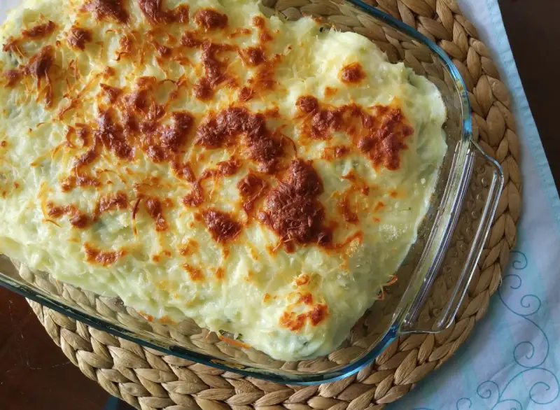 Parmentier de patata gratinado en fuente de cristal, con queso dorado y burbujeante. Un plato reconfortante y delicioso.