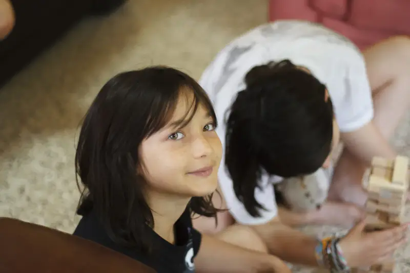 Deux enfants jouent à Jenga, une idée thème colonie. L'un regarde la caméra avec un sourire, l'autre est penché sur le jeu.