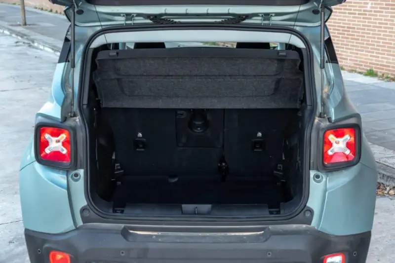 Maletero abierto de un Jeep Renegade color verde menta, mostrando el espacio de carga y la tapa retráctil.