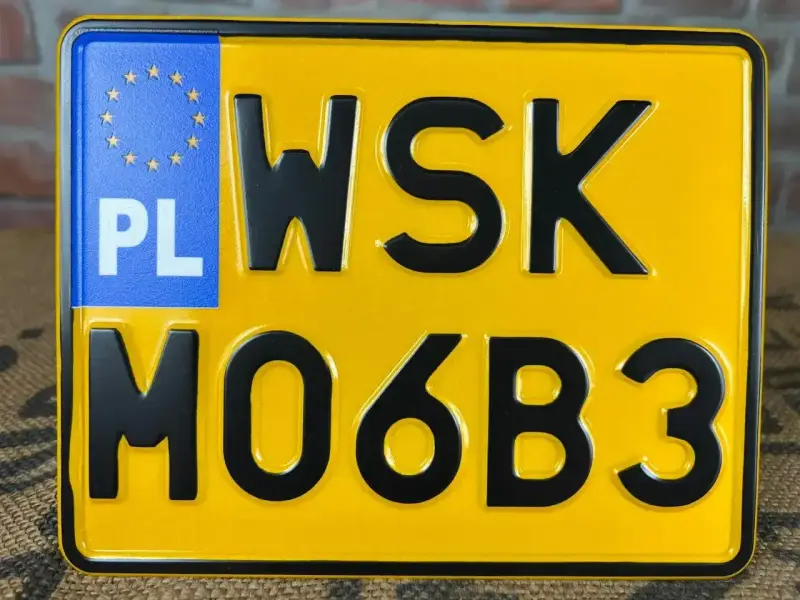 Żółta tablica rejestracyjna z czarnymi znakami "WSK MO6B3" i niebieskim polem "PL" z gwiazdkami UE.