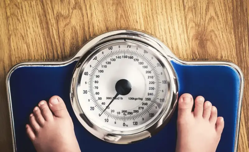 Dziecko staje na wadze. Zastanawiasz się, ile powinien ważyć 14 latek przy wzroście 170 cm?