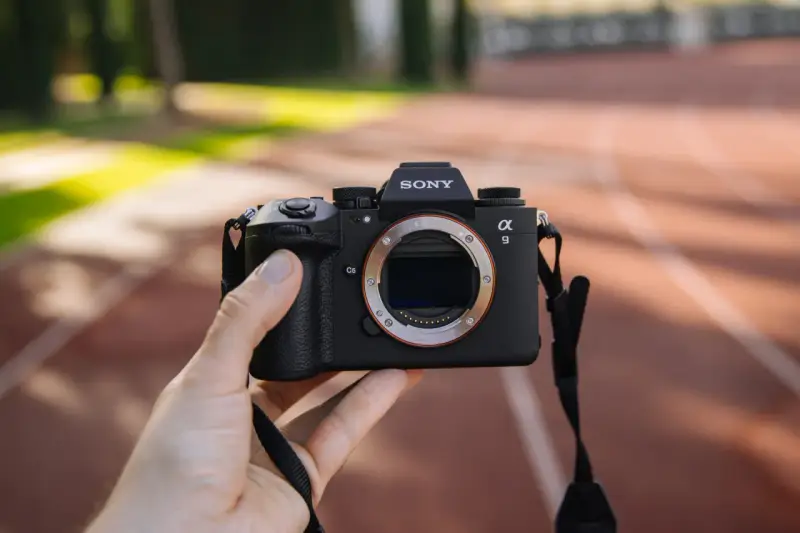 Dłoń trzyma aparat Sony Alpha 9 z obiektywem. Jego zaawansowany **global shutter** pozwala na uchwycenie dynamicznych scen bez zniekształceń.