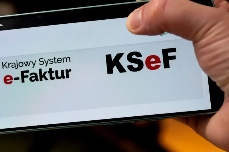 Palec dotyka ekranu telefonu z napisem "Krajowy System e-Faktur KSeF". To część polskiego ładu w finansach.