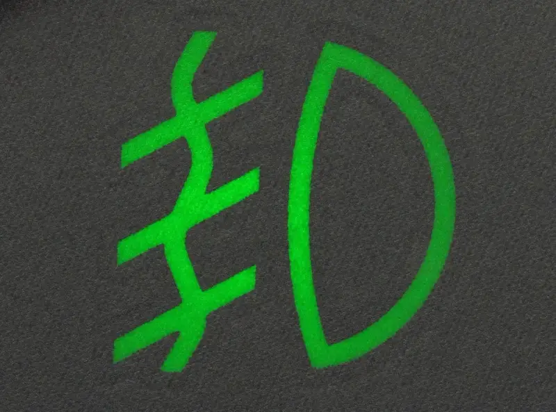 Zielony symbol przeciwmgielny na ciemnym tle.
