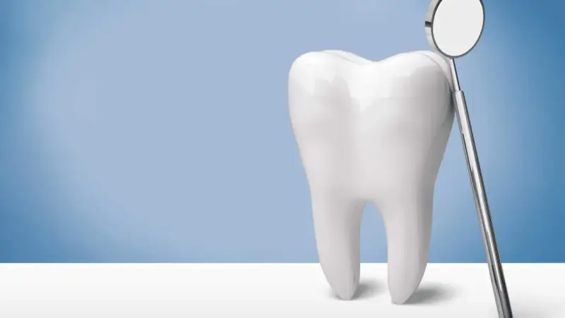 Biały ząb i lusterko dentystyczne. Pamiętaj, po piaskowaniu zębów nie wolno nic jeść przez godzinę.
