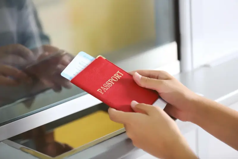 Ręce trzymają czerwony paszport z biletem lotniczym. Pamiętaj, czego nie wolno wywozić z Sycylii, by uniknąć problemów.