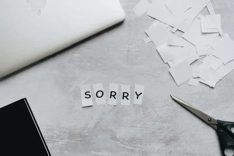 Litery wycięte z papieru układają się w napis "SORRY". Obok leżą nożyczki i stos białych skrawków, jakby ktoś tworzył piękny list na przeprosiny.