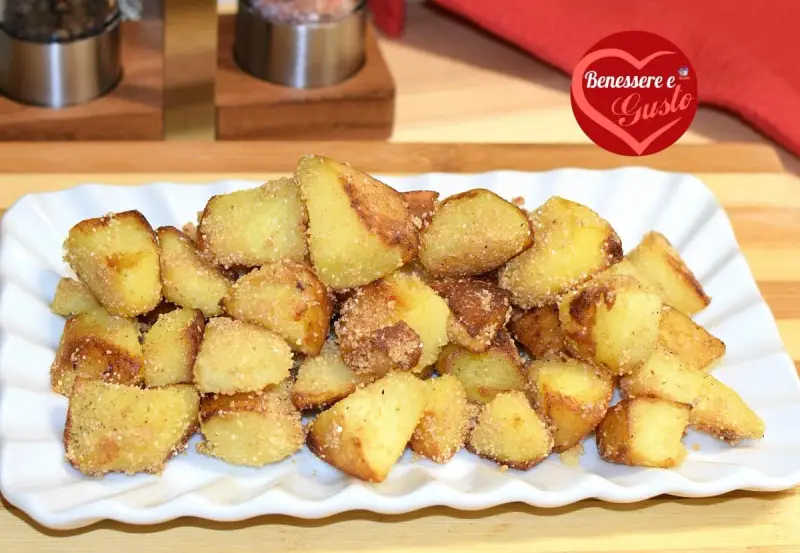 Patate sabbiose in padella, dorate e croccanti, servite su un piatto bianco. Un contorno irresistibile.