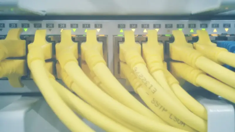 Żółte kable sieciowe podłączone do portów serwera. Zielone i pomarańczowe diody sygnalizują aktywność, a numery portów od 24 do 42 wskazują, które hosts windows są podłączone.