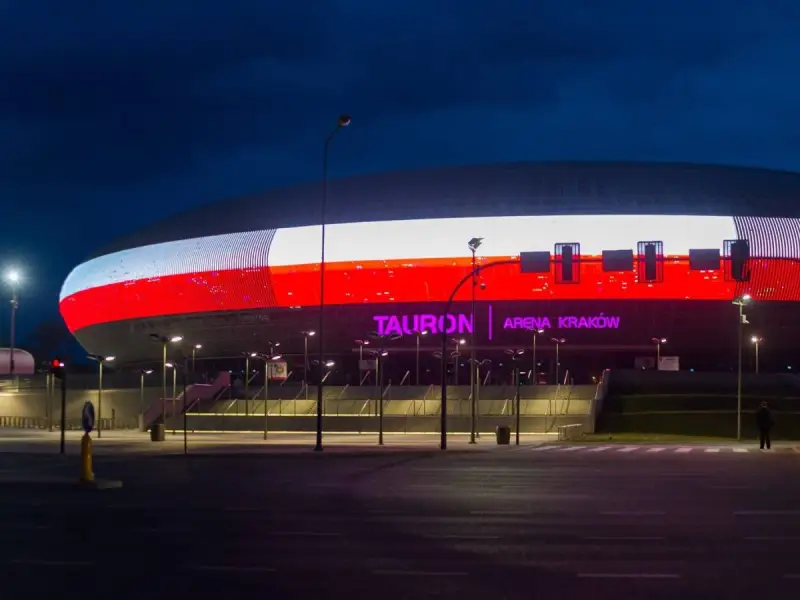 Tauron Arena Kraków nocą, z podświetloną fasadą w barwach narodowych. Obiekt mieści 15 tysięcy widzów, co czyni go jednym z największych w Polsce.