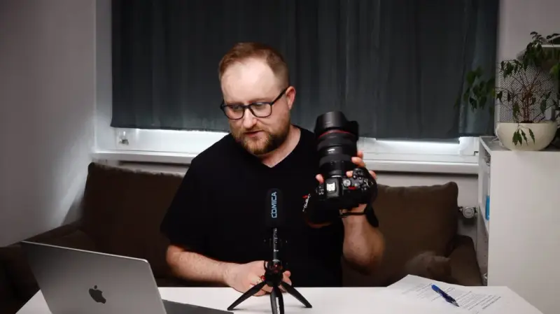 Mężczyzna prezentuje aparat fotograficzny, omawiając elementy kursu fotografii dla początkujących.