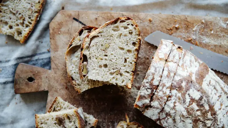 Frisches Brot mit Nüssen, perfekt **mit Dampf gebacken**, liegt auf einem Holzbrett.