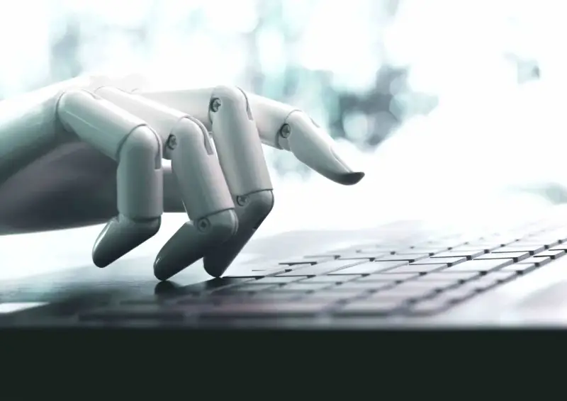 Mano robótica escribiendo en un teclado, una imagen que ilustra qué son los bots y su interacción con la tecnología.