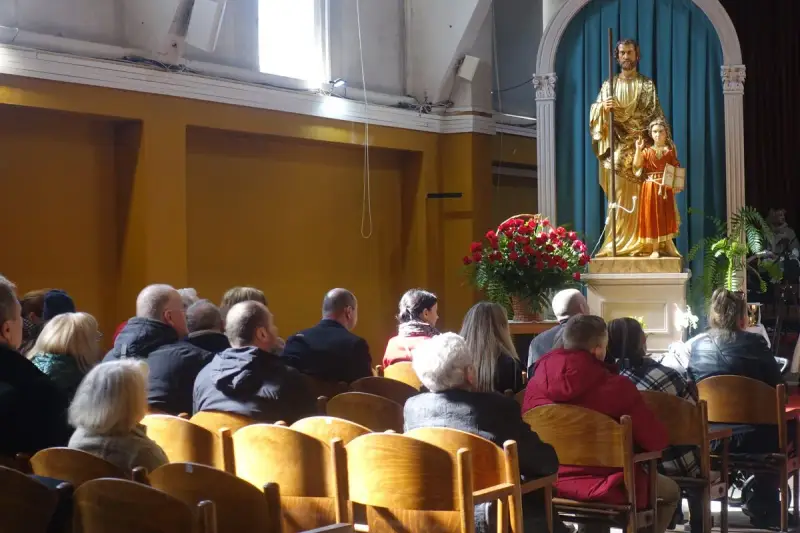 Ludzie w kościele, przed ołtarzem z figurą św. Józefa i Dzieciątka Jezus. W tle bukiet czerwonych róż. Sanktuarium Matki Bożej Częstochowskiej.